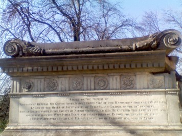 A monument to an English general; the inscription reads 'Sacred to the memory of Lieutenant General Sir George Airey, Knight Commander of the Hanoverian Order of the Guelph, Knight of the Order of Saint Joseph of Tuscany, and Colonel of the 59th Regiment. Born at Killingworth, in the County of Northumberland, A.D. 1759. He entered the Army in 1779, having served in the West Indies, Egypt, and various parts of Europe for upwards of half a Century, departed this life, at Paris, on the 18th day of February 1855.'