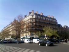 Street corner on the Boulevard Saint-Germain. In front of the famous café Les Deux Magots, a green-black car traverses the intersection
